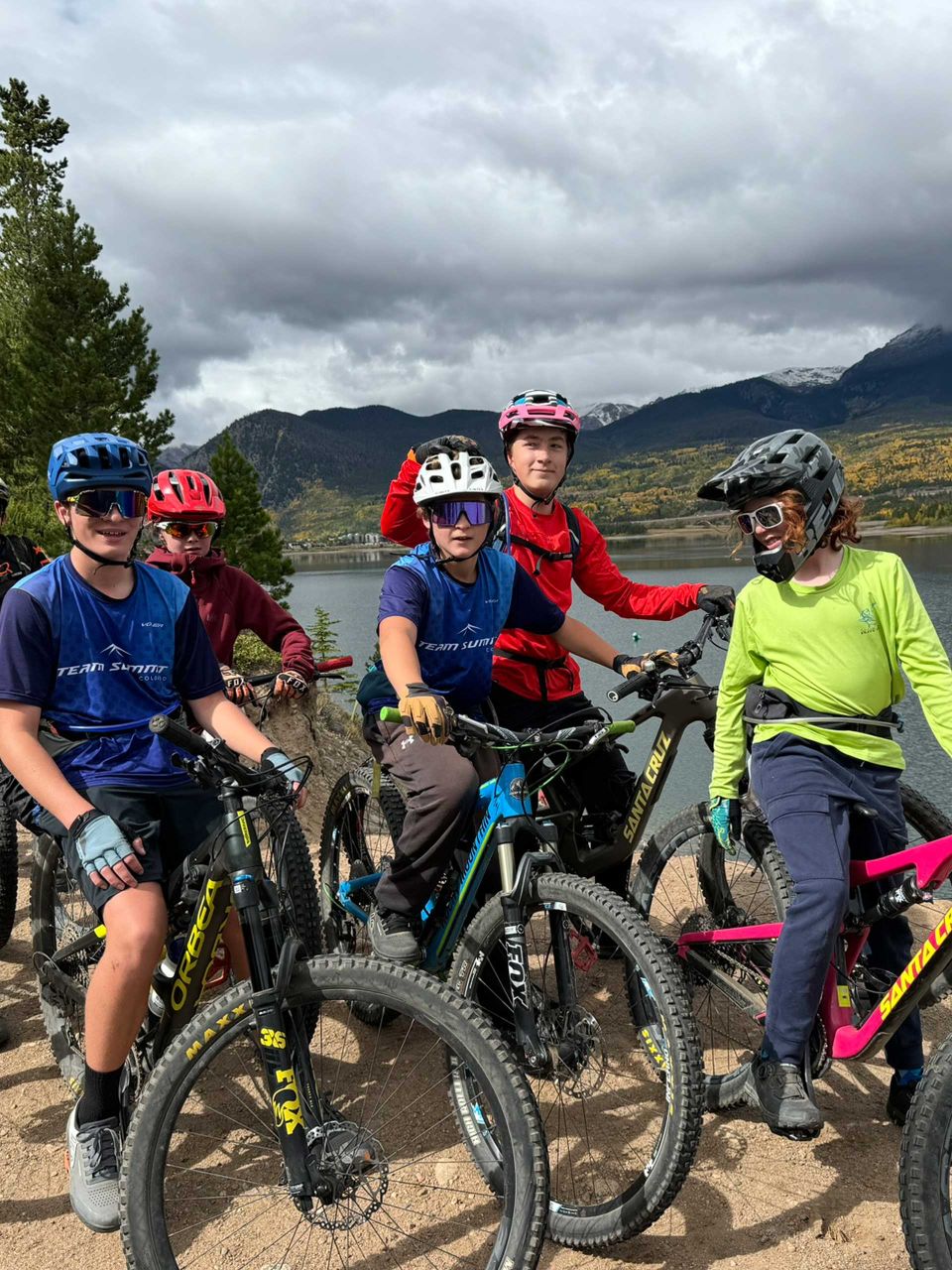 young mountain bikers out on the trail stopping by a lake to take a group photo