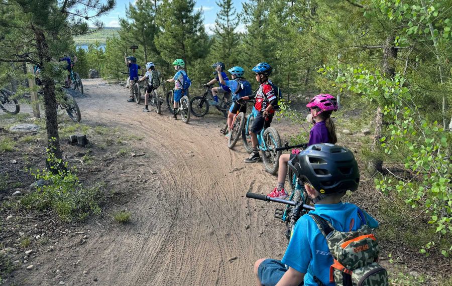 beginner mountain bikers on a trail listening to a coach