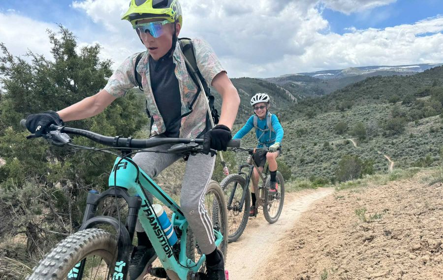 middle school mountain bikers ride on single track trail surrounded by sage brush