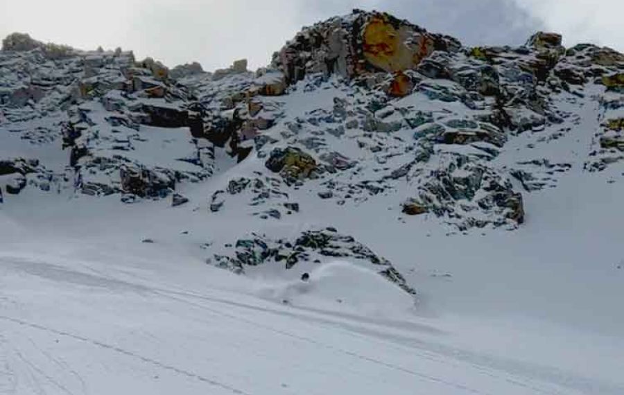 powder skier big mountain in the background in a blue sky